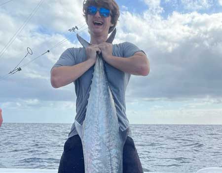 Man holds up fish caught on his trip in two hands