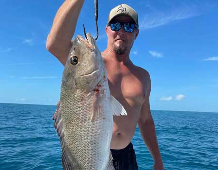 Man aboard boat holds up a huge fish
