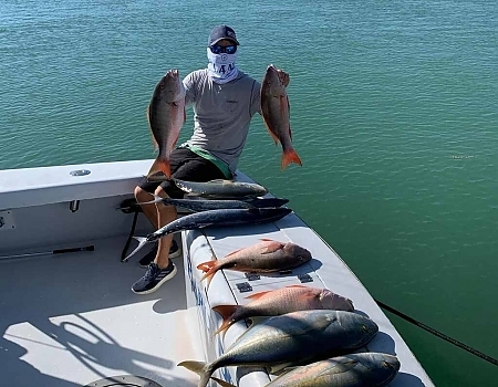 Man holds up fish caught on his trip in two hands